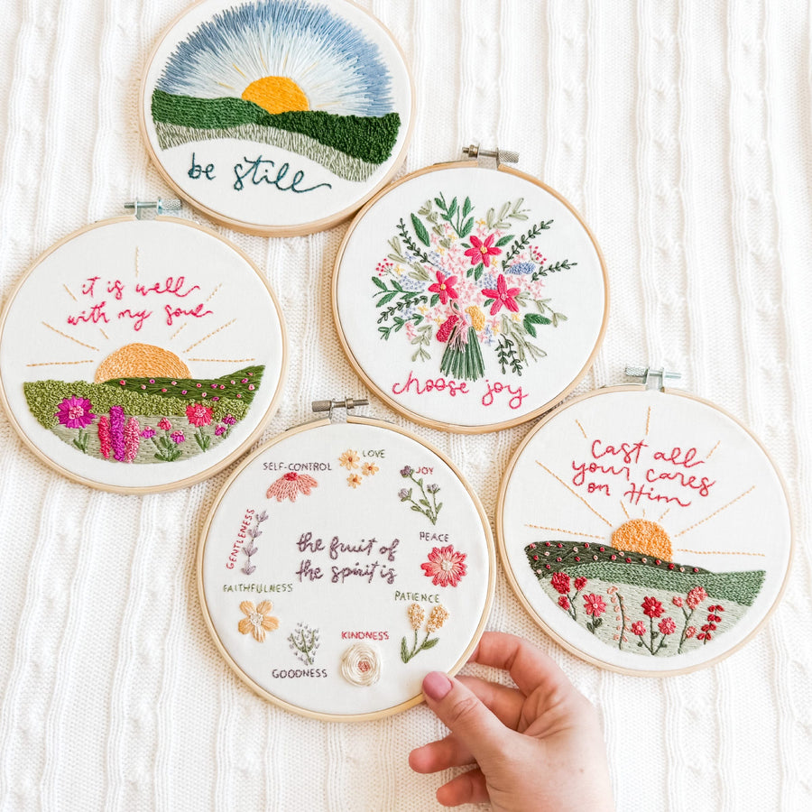 Hands holding finished Christian embroidery hoops